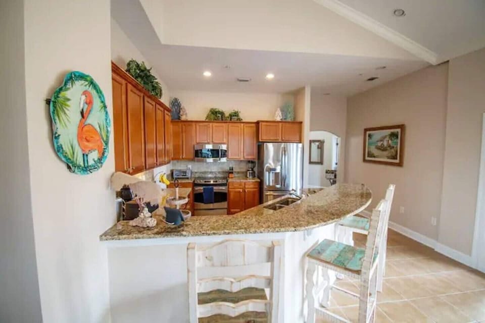 The open kitchen flows seamlessly into the living and dining areas, featuring a bar, granite countertops, and stainless steel appliances, perfect for entertaining and family gatherings.