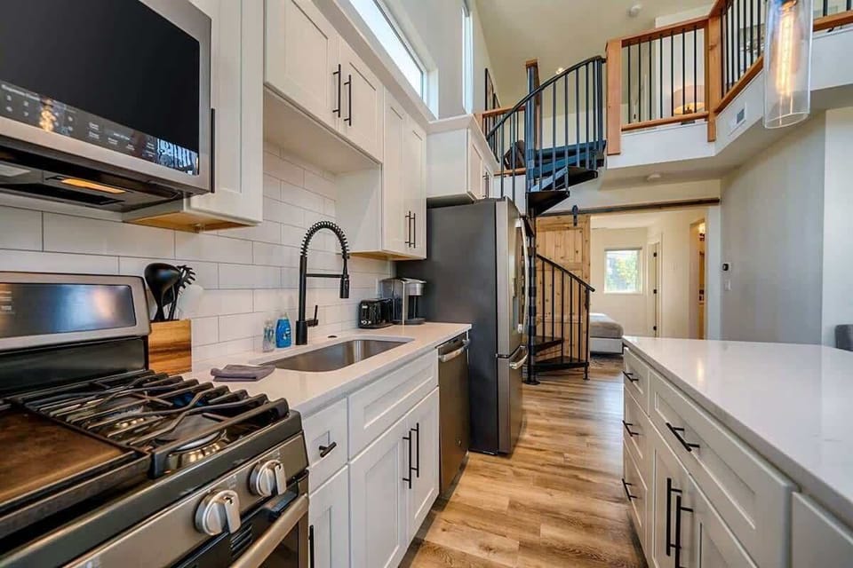 The space features a fully equipped kitchen on the main floor, with stairs leading up to a loft area.