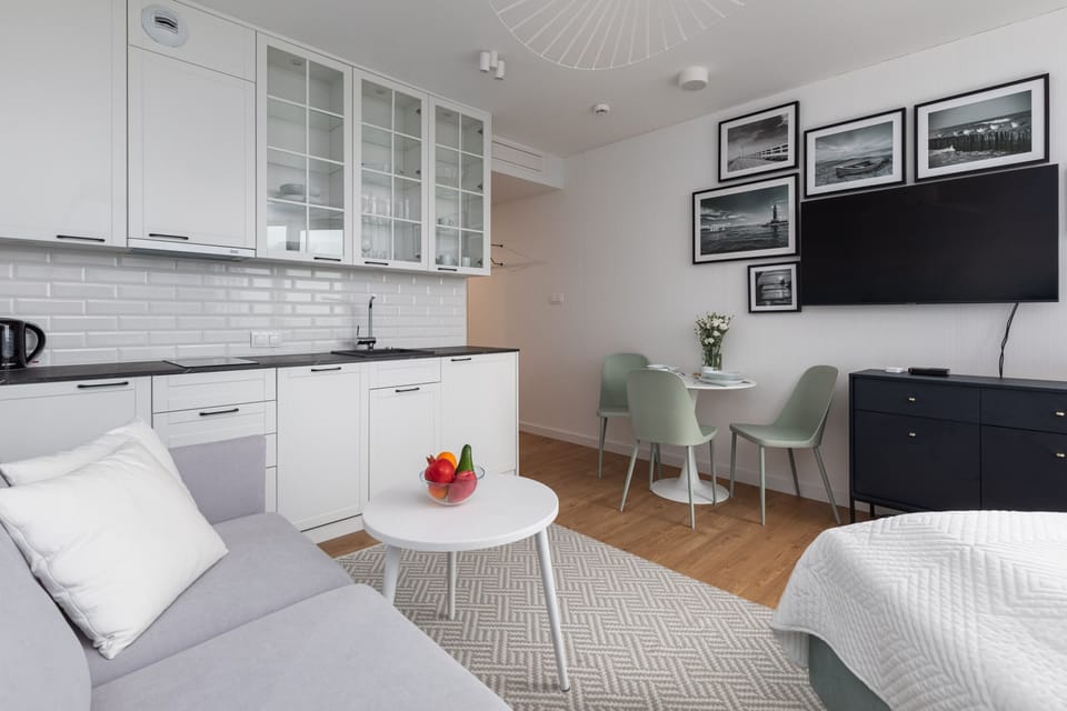 A bright, modern studio with a comfortable bed, a round coffee table, and large windows overlooking the outdoors.