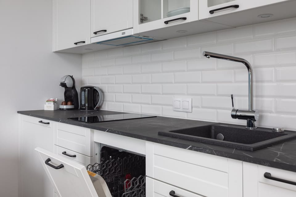 A compact kitchen with white cabinetry, a black countertop, and modern appliances, offering everything you need for cooking.