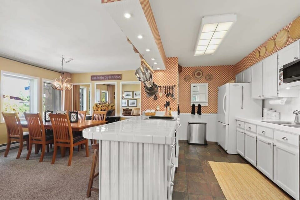 The view into the open kitchen and dining room where you will find a large kitchen bar with three bar stools as a bridge between the two spaces.