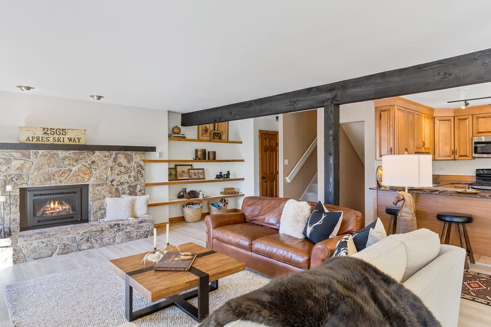 Different view of the living room showing the built in book case next to the fireplace, stairwell, and part of the kitchen.
