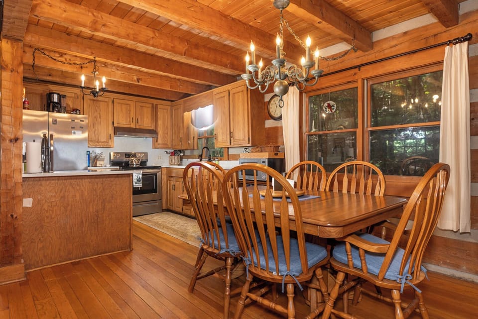 Gather around this warm wood dining table under charming chandelier light, with your fully-equipped kitchen just steps away for effortless meal prep.