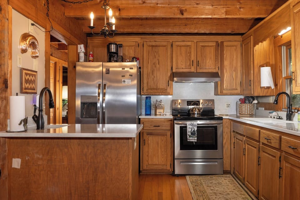 Your rustic kitchen invites culinary creativity with warm wood cabinetry, stainless steel appliances, and charming exposed beam ceilings. Plenty of counter space and modern conveniences await.