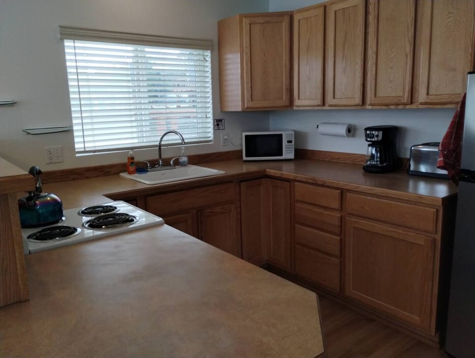 Waterfront Cabin – Kitchen Equipped with Fridge, 12-Cup Drip Coffee Maker, Toaster, Microwave, 4-burner stove with Oven, Tea Kettle, Coffee, Creamer, Sugar, Tea, Filters, and Basic Cooking Essentials.