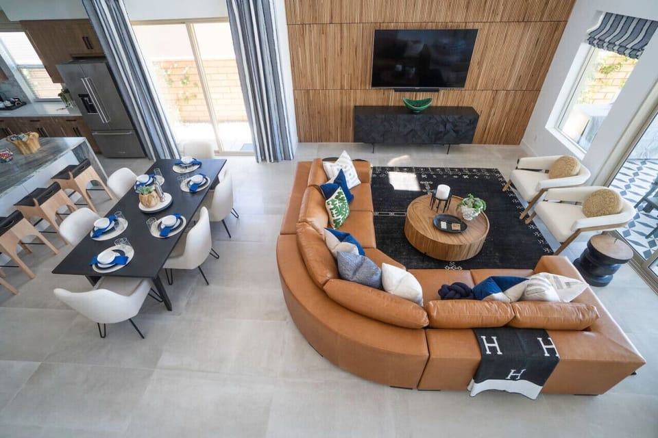 Lofted view of the living room w/ curved sofa, fireplace & elegant dining setup