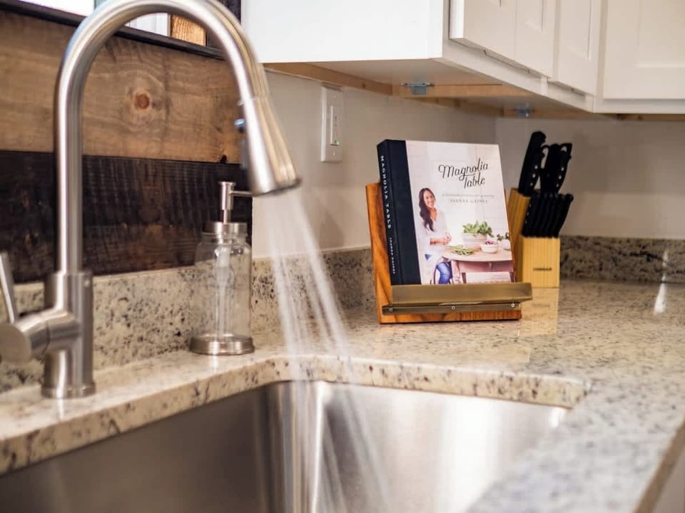 Close-up of kitchen sink w/ modern faucet & granite countertop workspace