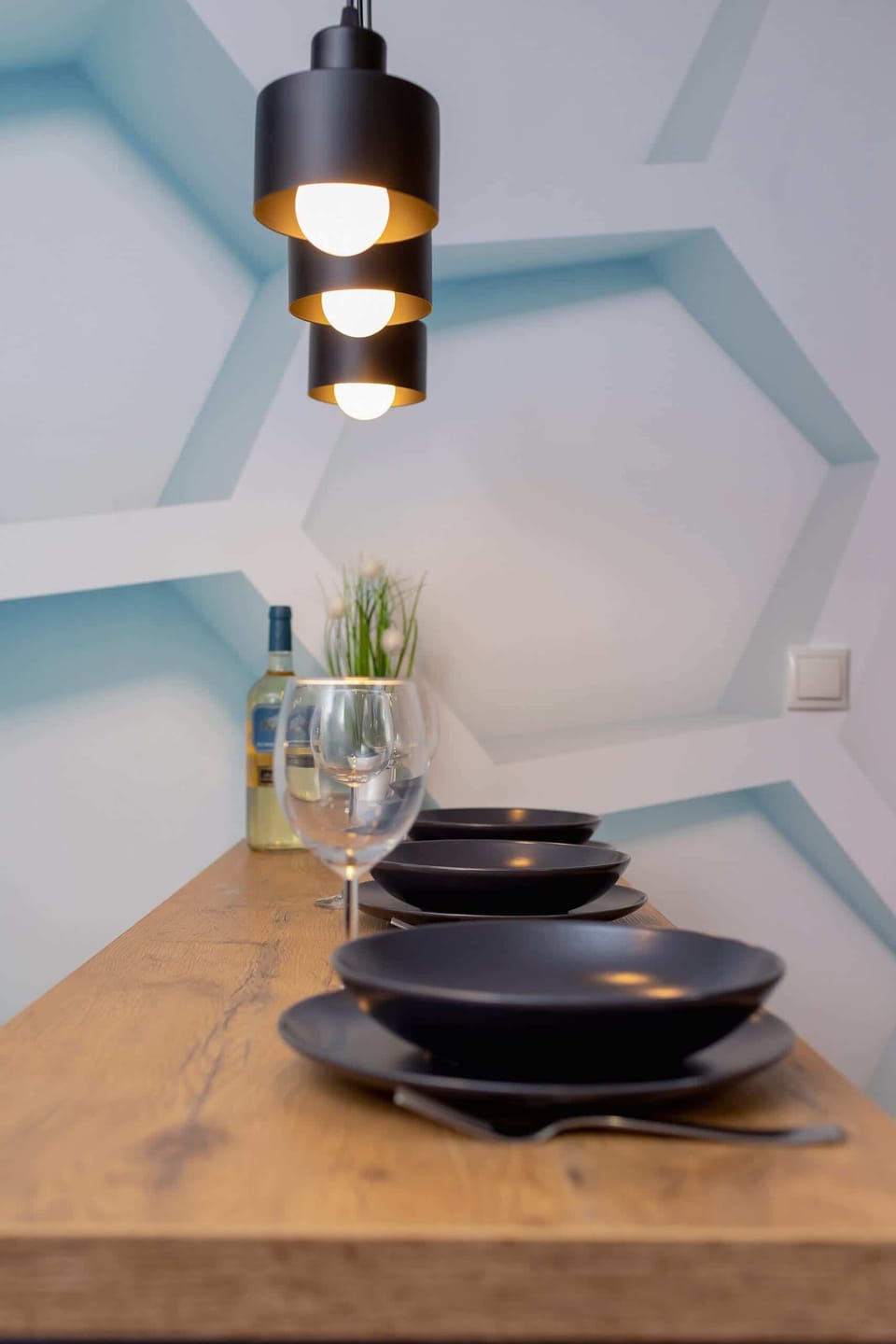 A dining setup with contemporary lighting and tableware, adding a touch of elegance to the space.
