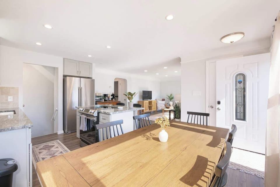 Open floorplan entry leads into a spacious living/dining area opening to a modern kitchen with central island. A hallway off the kitchen serves two bedrooms and a full bath, with stairs to the upper level tucked neatly by the entrance. ✨