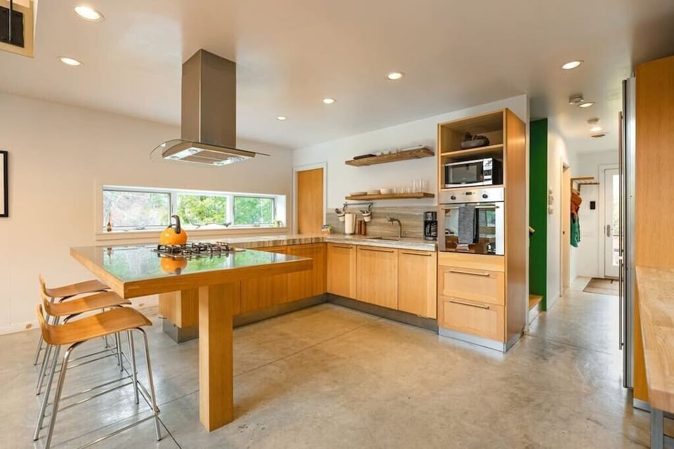Our open-concept kitchen with oven, gas range,  microwave, coffee maker, bar seating and dining table.