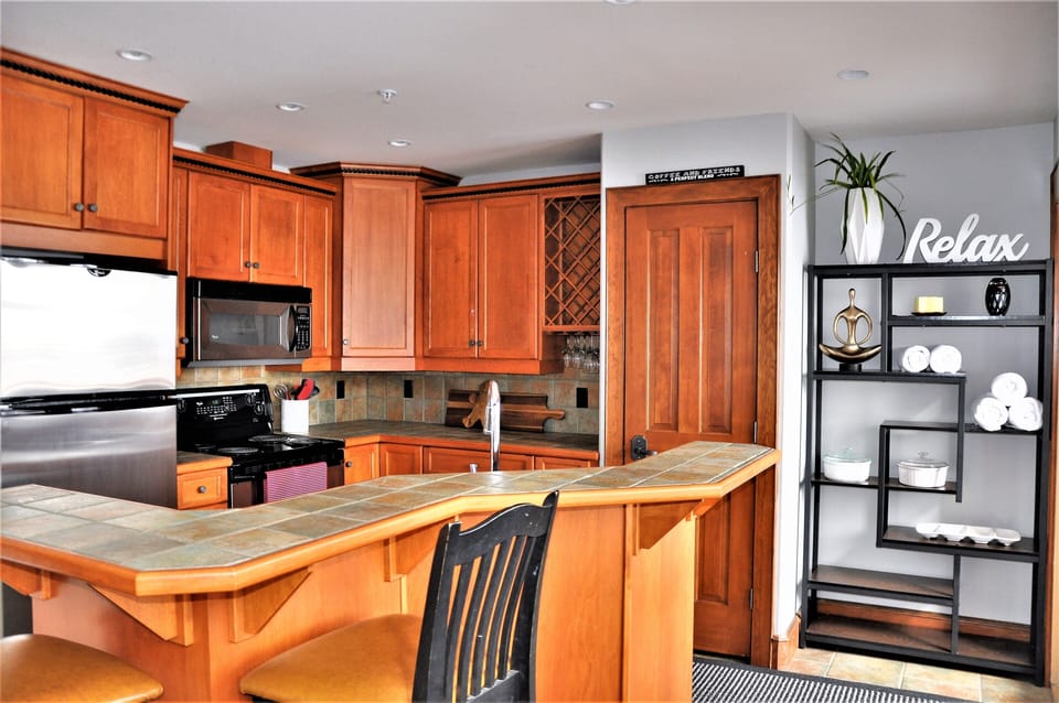 Open kitchen with stainless appliances, wine rack and bar seating.