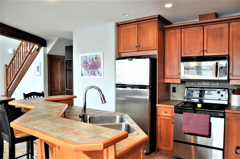 Open kitchen with stainless appliances, wine rack and bar seating.