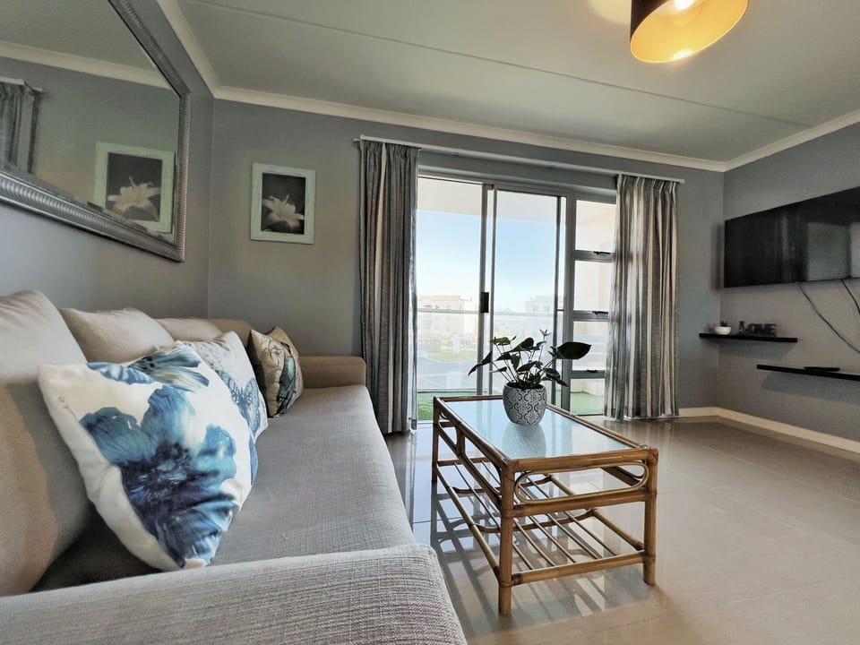 Open lounge with four seater couch + dinner table + four chairs + flat TV