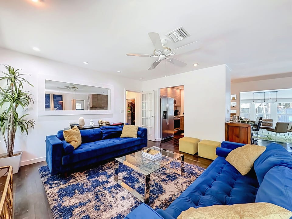 Living room with two velvet sofas, area rug and open flow to the kitchen and dining room.