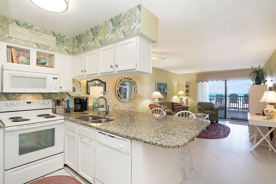 Your beachfront kitchen features granite counters and modern appliances, opening to a living space with stunning ocean views.