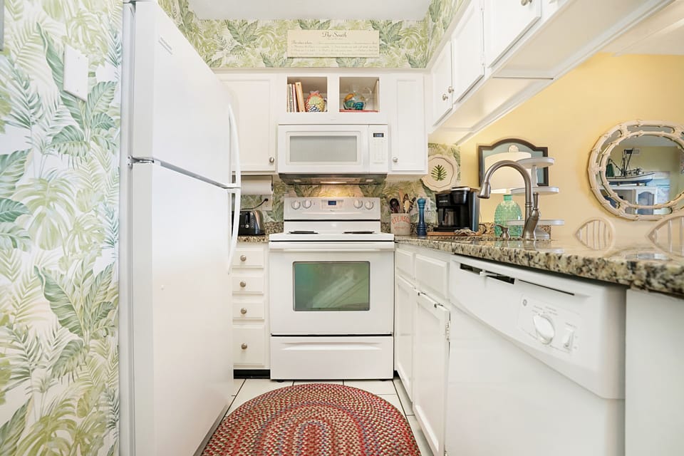 Your tropical-themed kitchen features full appliances and charming palm wallpaper, making meal prep feel like a vacation.