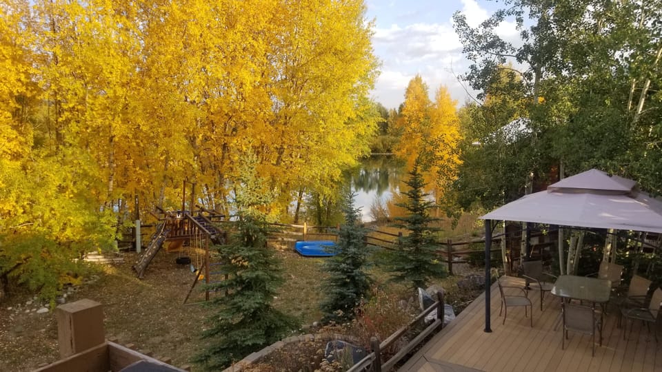 Beautiful backyard area features a playset, pond, and large private deck area.