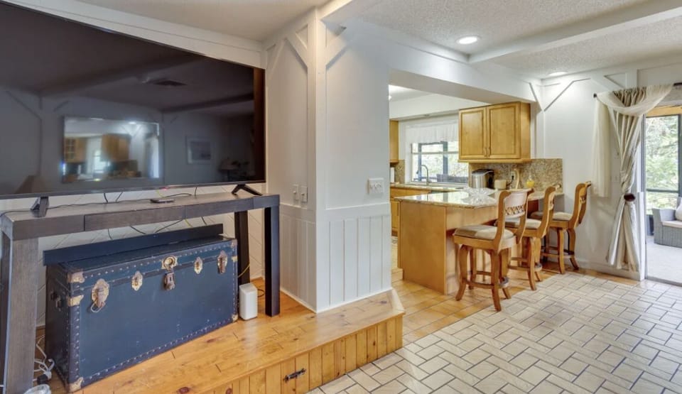 Den and kitchen area with bar stool seating and TV. 
