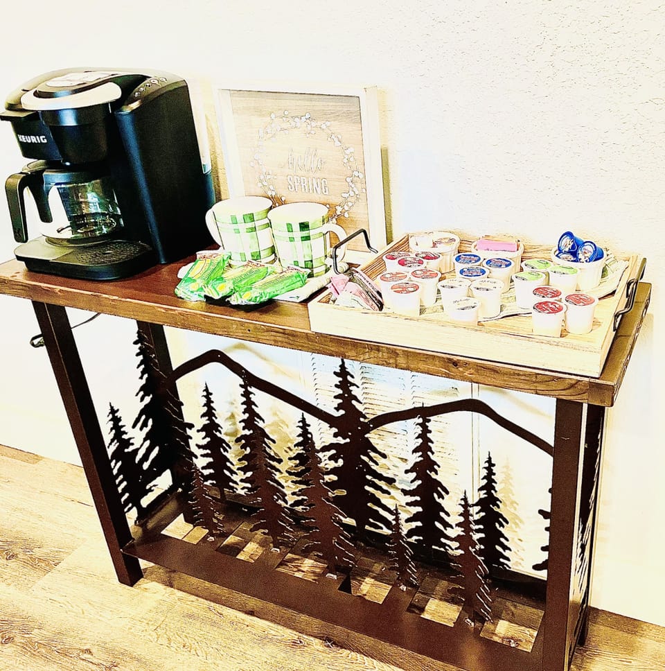 Hospitality table has Keurig/coffee maker, assorted K-cups, tea, sugar and creme