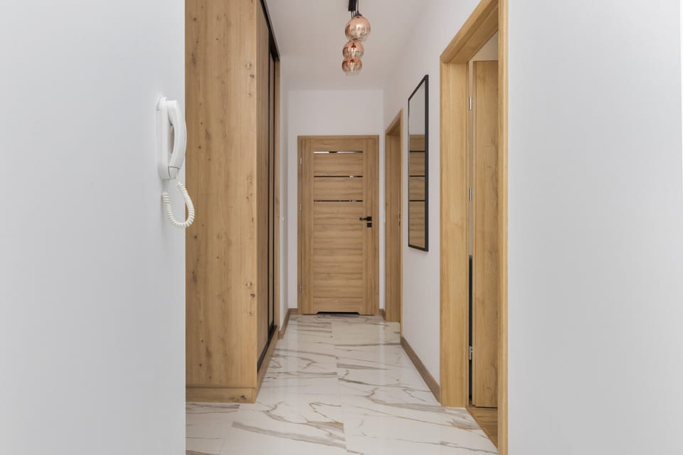 A hallway with wooden doors and tiled flooring leading to different rooms.
