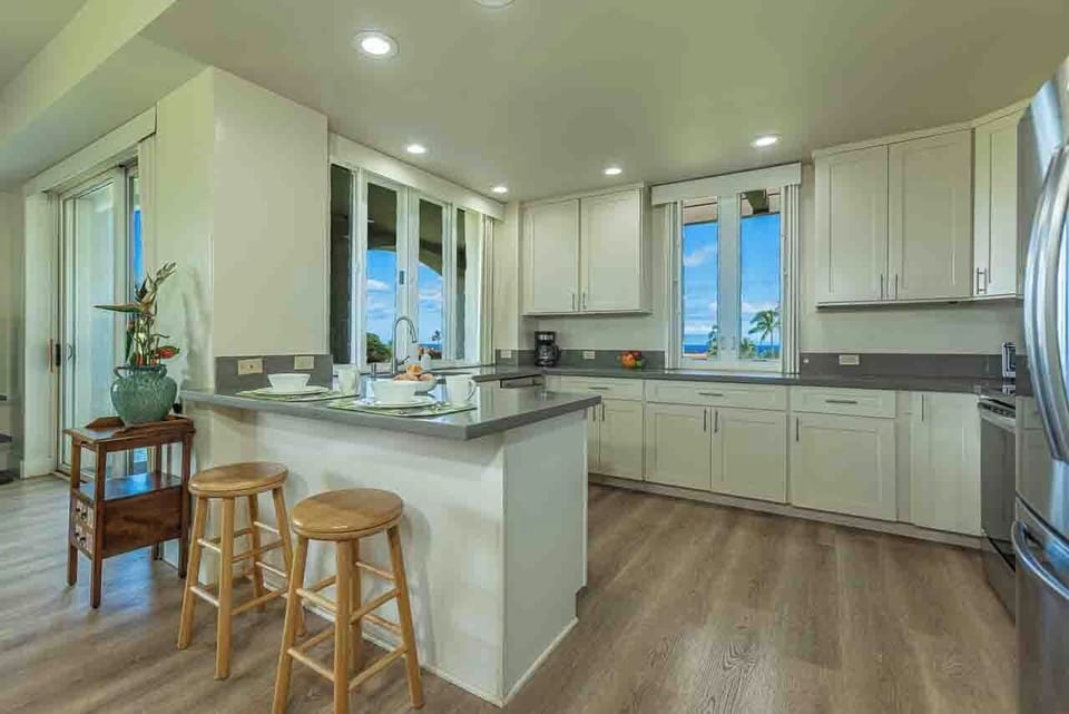 Your fully equipped kitchen features modern appliances and a breakfast bar with seating—perfect for preparing meals while enjoying stunning ocean views through the large windows.