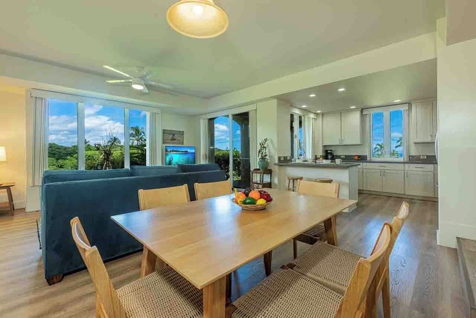Gather around the natural wood table where your group can share meals and laughter, with lush garden views framing the open, sunlit space and a full kitchen ready for your culinary adventures.
