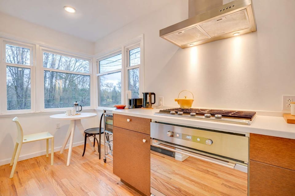 Bright kitchen with modern appliances and a charming breakfast nook surrounded by windows and peaceful outdoor views.
