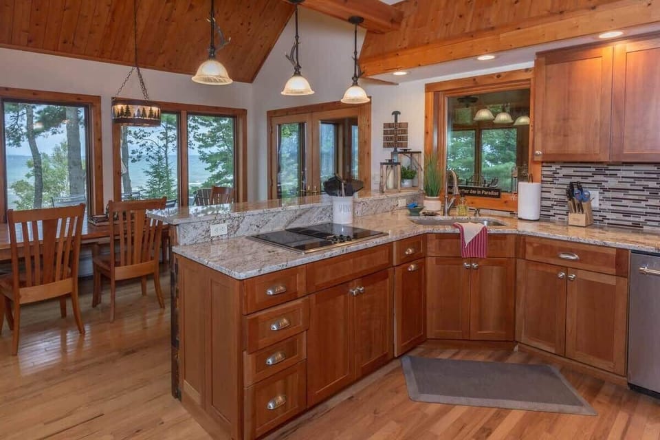 Full kitchen view showing the stainless appliances, generous counter space, and Lake Superior visible through every window