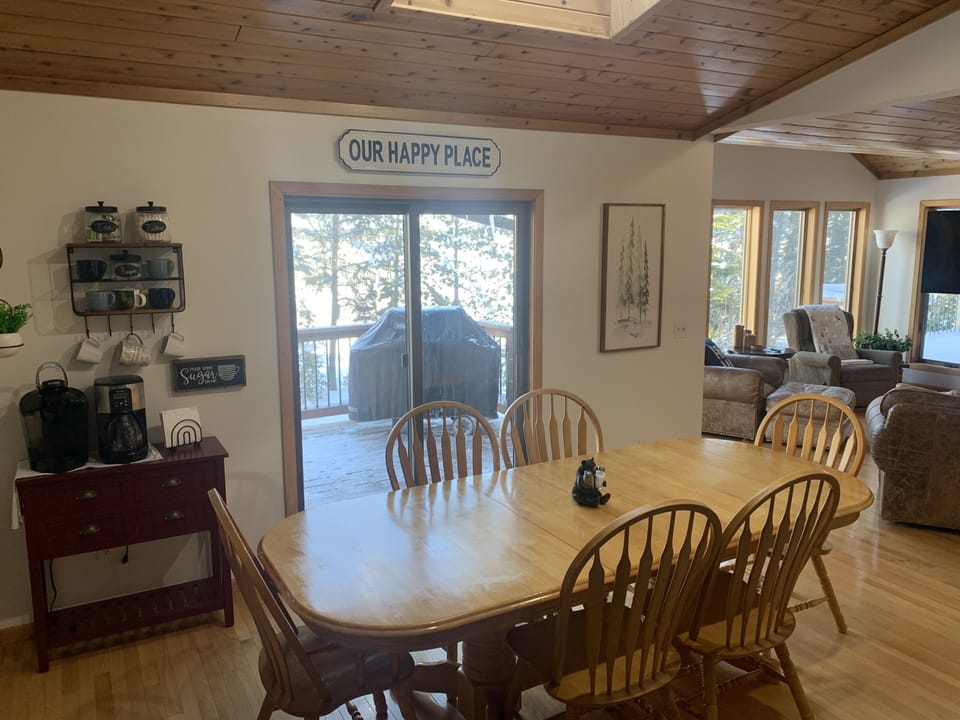 Two coffee makers in dining area. Large table for meal time. 