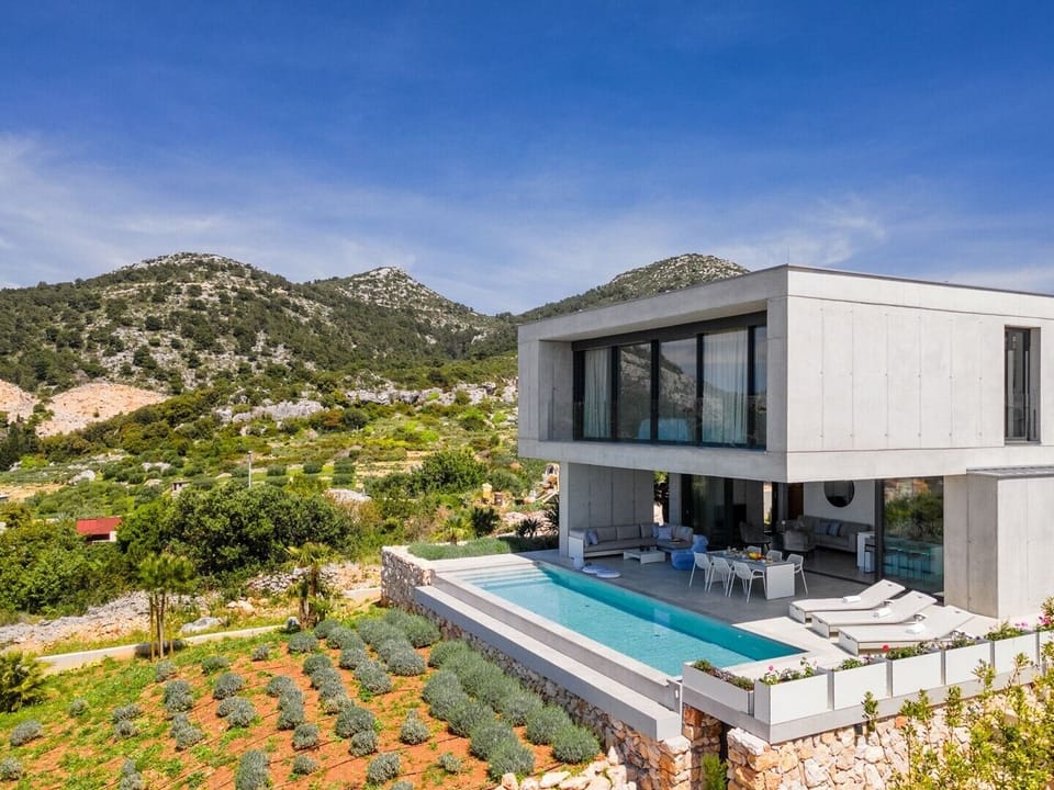 View of the luxury Dalmatian villa Omnia Hvar with private pool surrounded by deckchairs for vacation