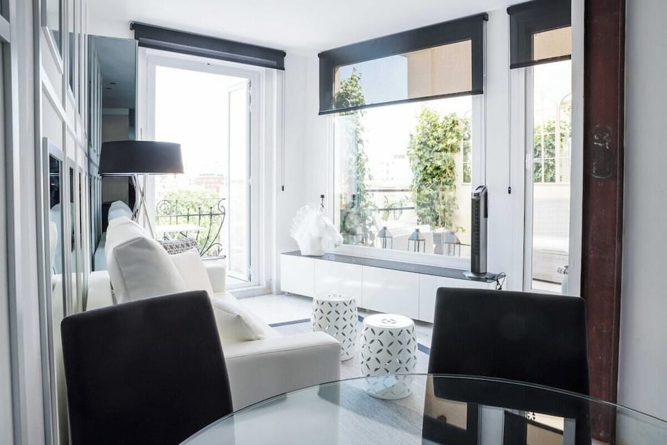 Dining-  room, with sofa, table and design furniture, TV and views  of the terrace of the apartment.