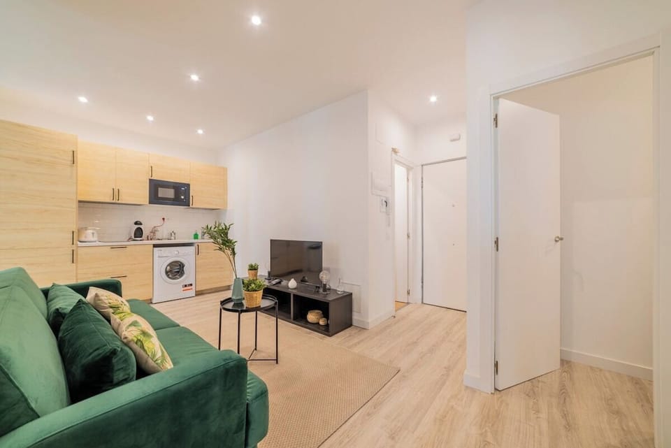 General view of the living room with the kitchen in the background and access door to the apartment