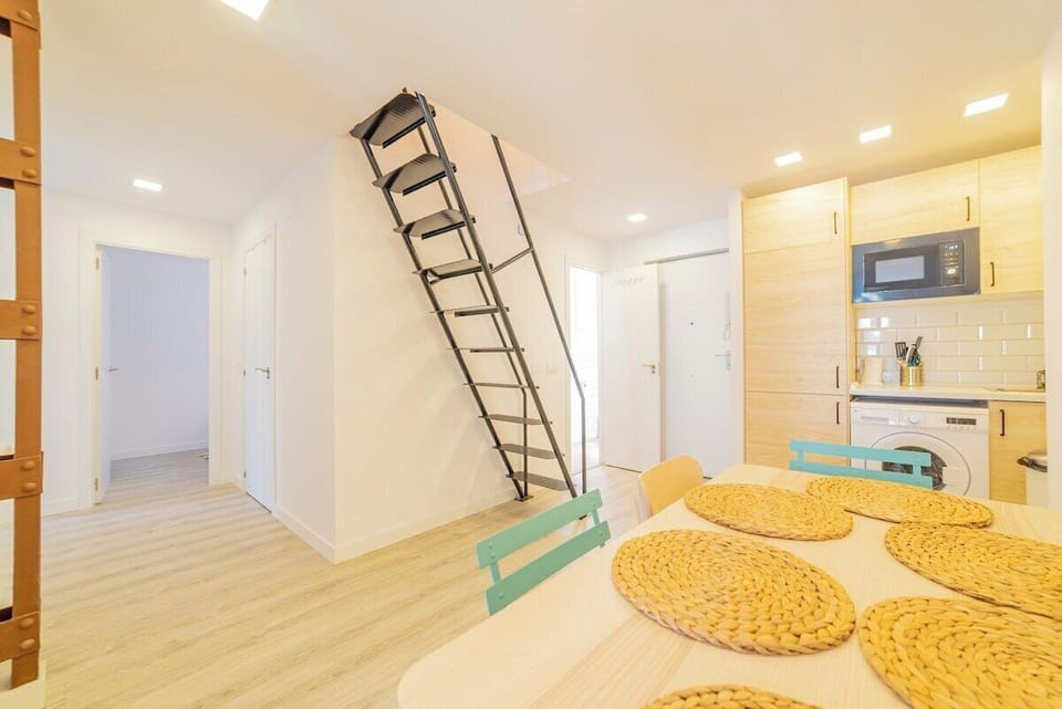 View of the dining room with the kitchen in the background and access stairs to the upper bedroom
