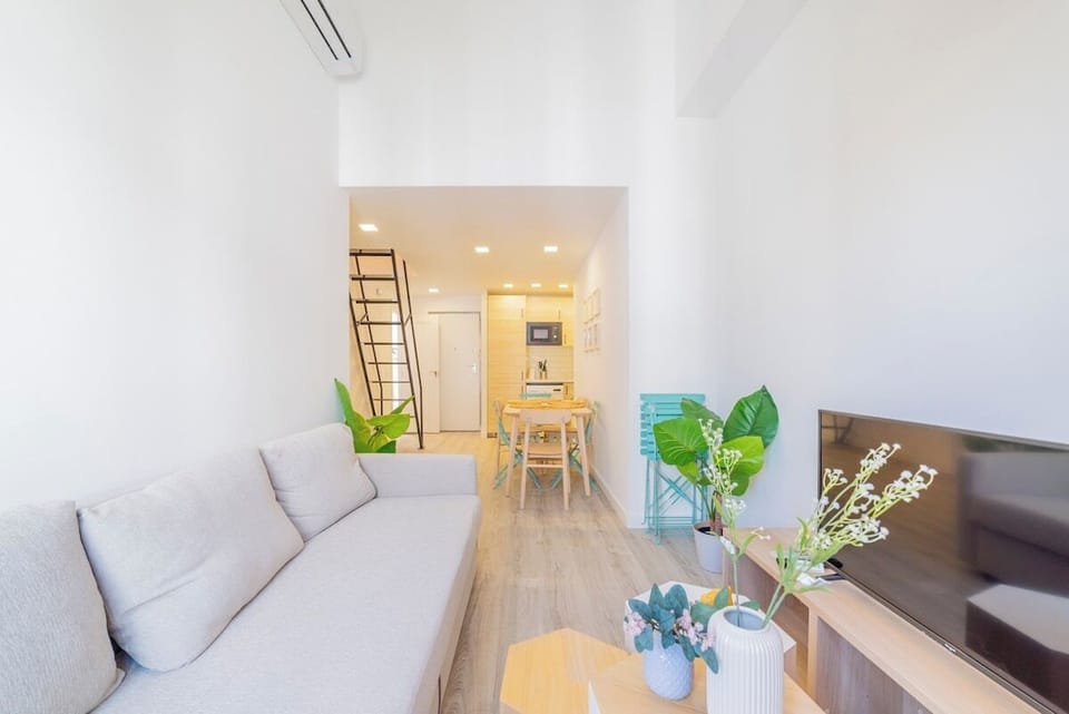 General view of the living room with kitchen in the background and access stairs to the upper bedroom