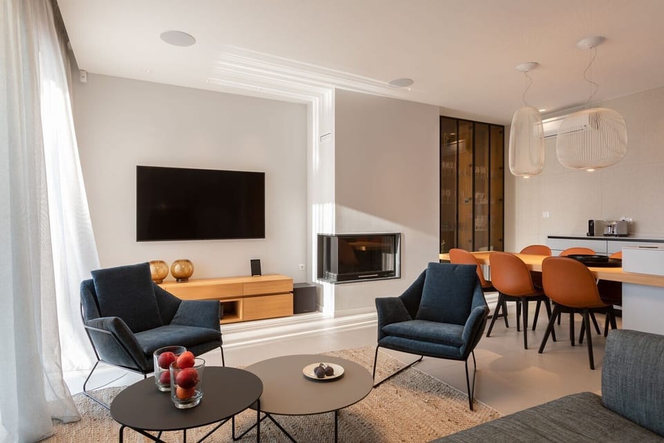 Comfortable living area with armchairs, LCD TV and fireplace and kitchen with kitchen island, toaster and coffee machine