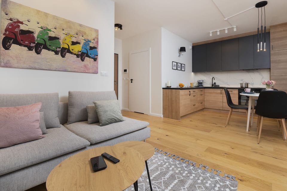 A modern living room with a light sofa, colorful artwork, and a cozy rug.
