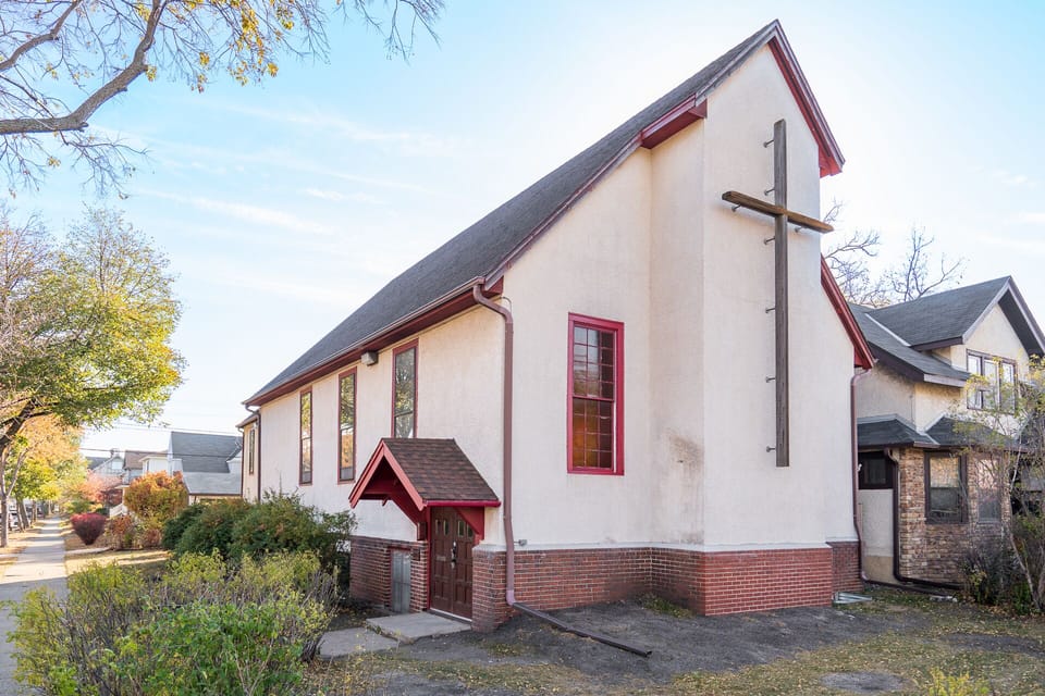Charming converted church with distinctive architecture and peaceful residential setting surrounded by mature trees and neighboring homes.