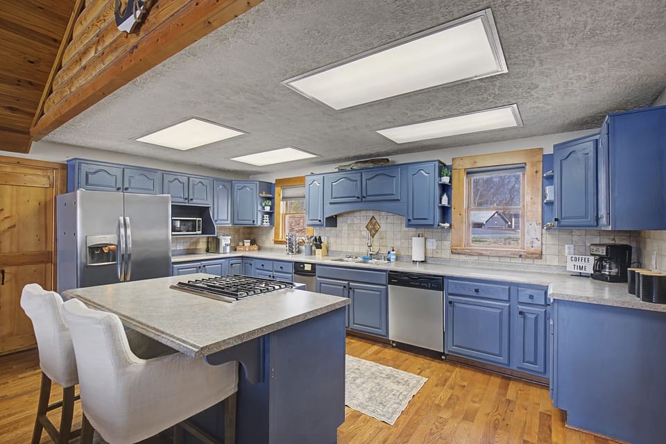 Fully equipped kitchen with striking blue cabinetry, natural wood details, and a large island with seating.