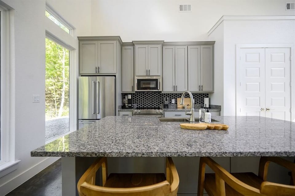 Kitchen: Sleek granite countertop, modern appliances, and nature views await your culinary adventures!