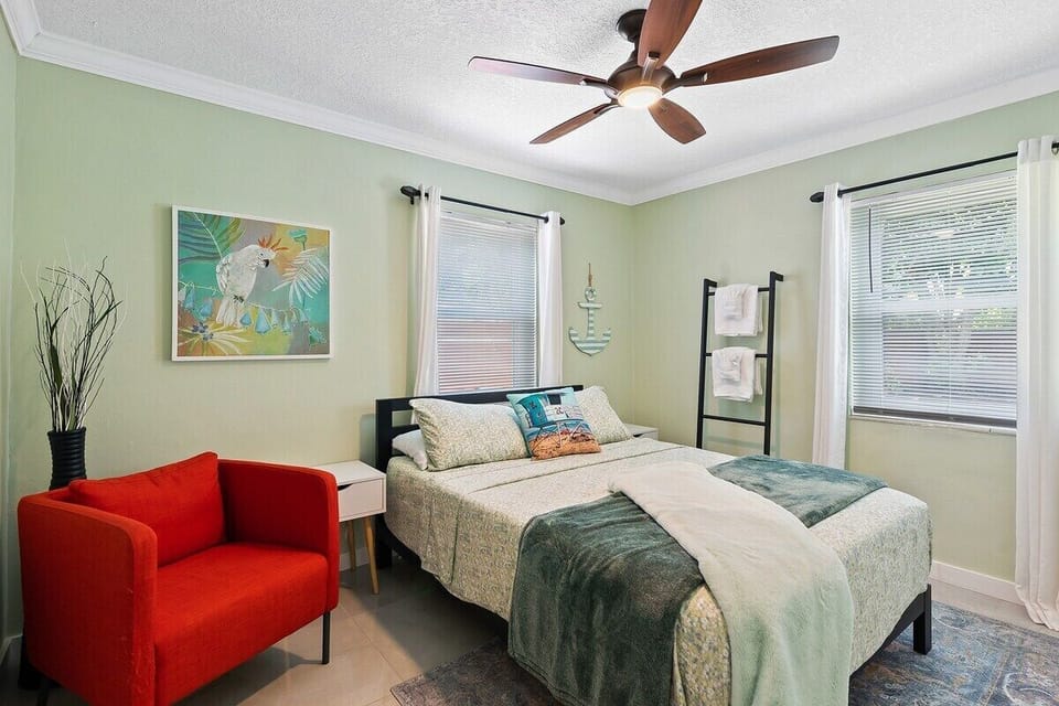 THE THIRD BEDROOM HAS BACKYARD VIEWS AND OFFERS A QUEEN SIZE BED, SMART TV, SOFA CHAIR, CEILING FAN AND CLOSET SPACE. A FULL BATHROOM IS LOCATED IN THE HALLWAY JUST OUTSIDE OF THIS BEDROOM
