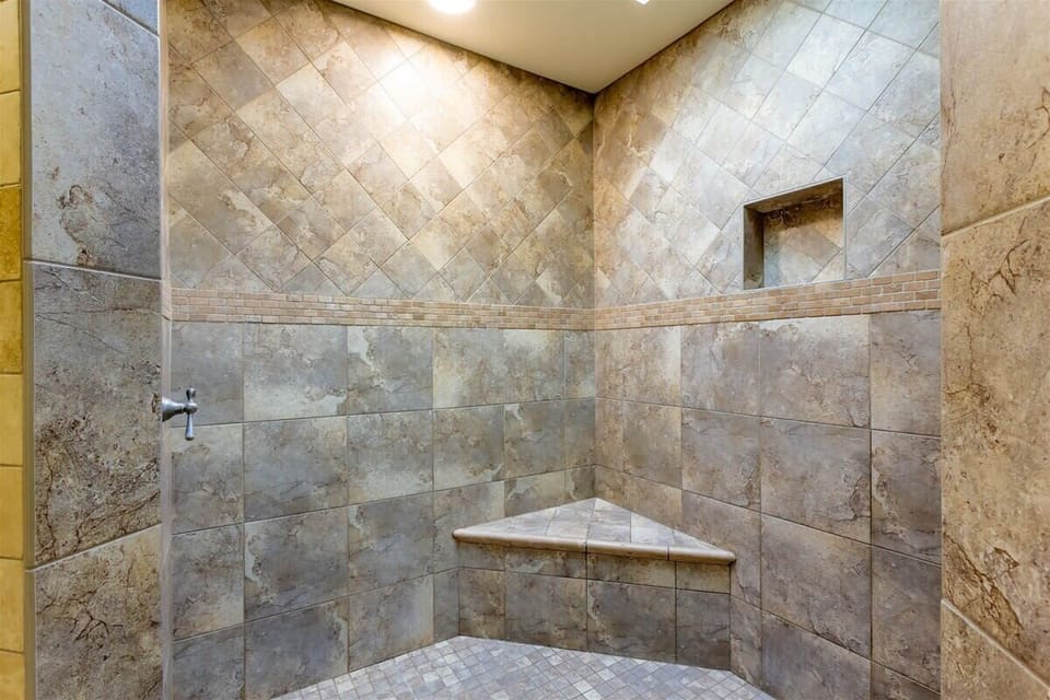 The master bathroom features a large open-air shower, double sinks, and a walk-in closet
