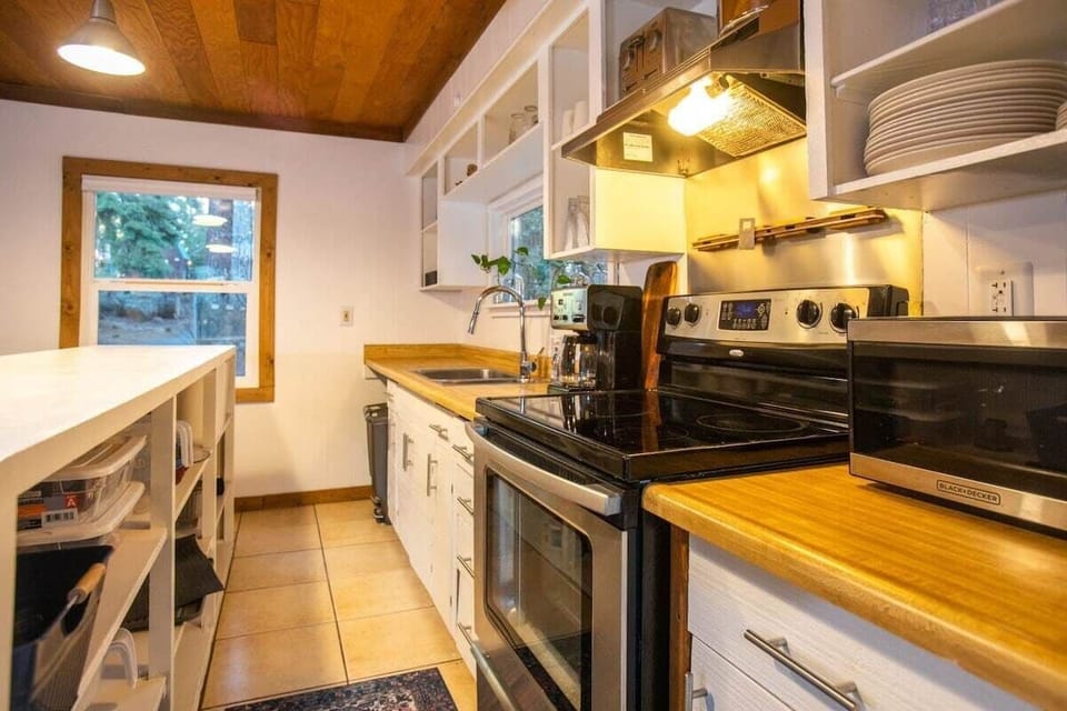 The kitchen features stainless steel appliances, charming exposed shelving, and a large kitchen bar with seating for 6.