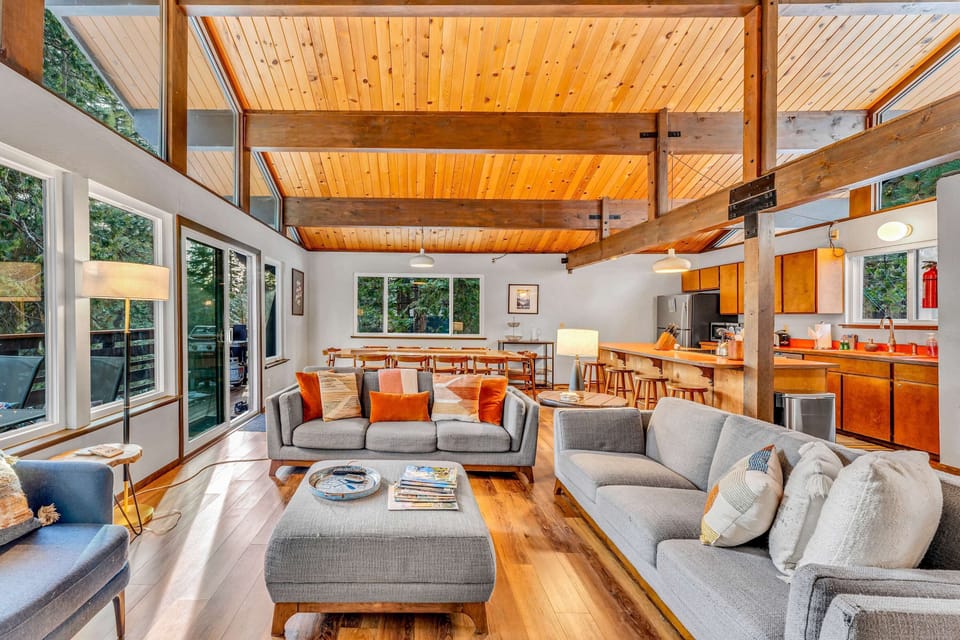 Living Room: 2 couches, 1 chair, wood-burning fireplace, 55” Smart TV, access to deck
