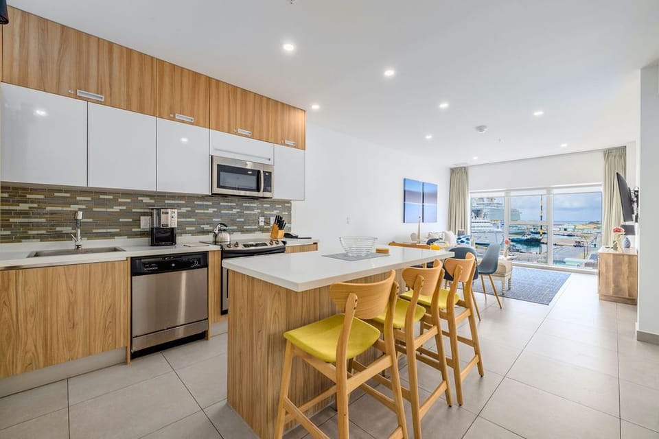 A modern fitness center spans floor-to-ceiling windows overlooking the sparkling sea, where treadmills, bikes, and weights await your waterfront workout.
