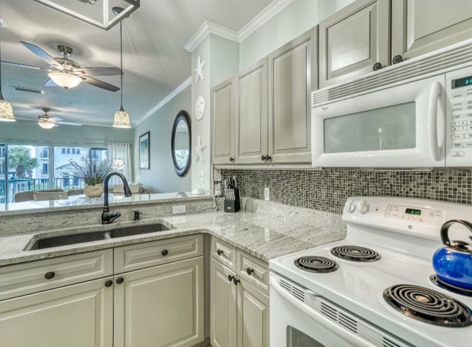 Cook your favorite meals in this bright, fully-equipped kitchen with granite counters, modern appliances, and charming mosaic backsplash.