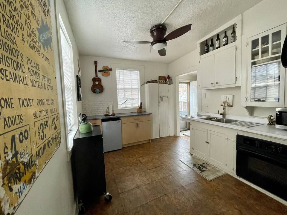 Kitchen features mini fridge, tool box full of utensils. 