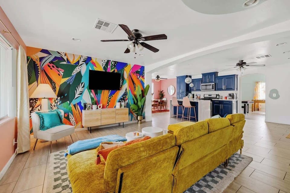 Open living space w/ vibrant mural, comfy seating, & seamless flow into the kitchen.