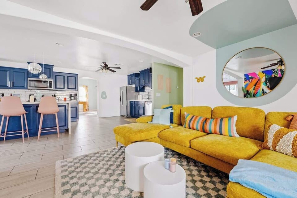 Open-concept living area w/ vibrant decor, soft textures, & inviting seating throughout.