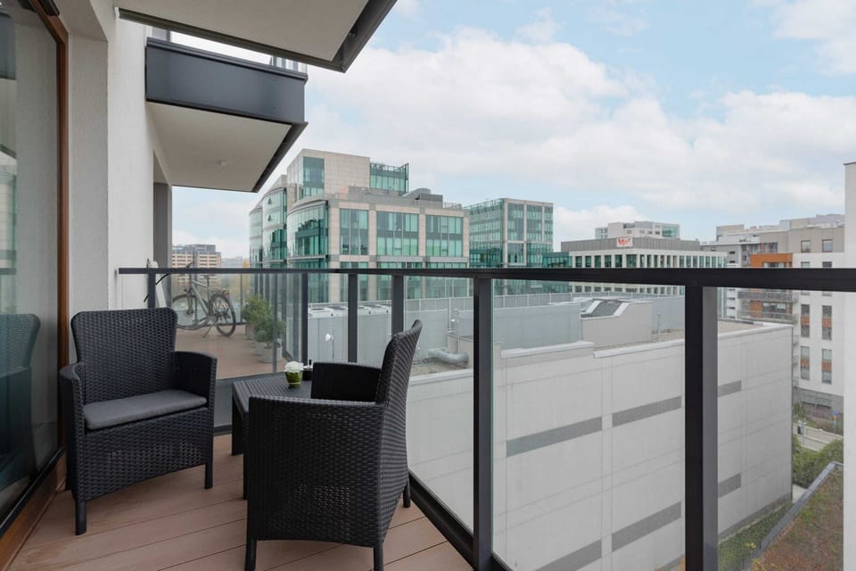 A balcony with a seating area offering views of the surrounding buildings.
