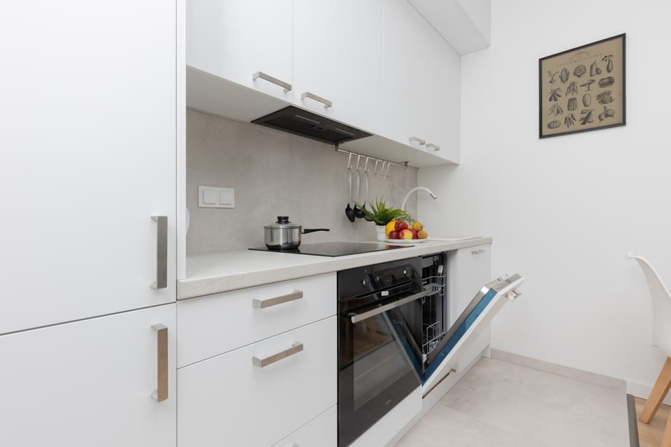 A modern kitchen with white appliances, cabinets, and wooden countertops.
